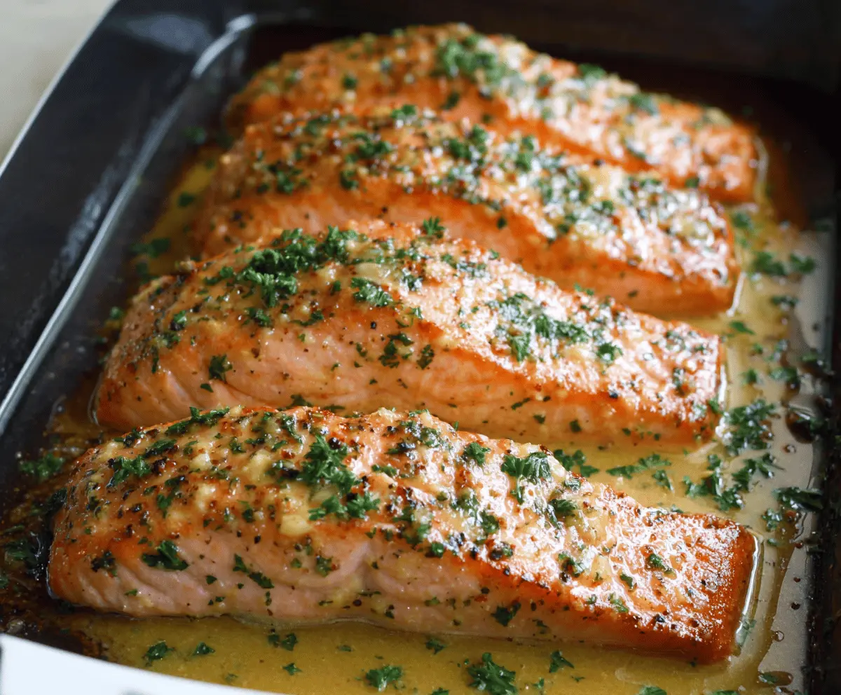 Delicious baked salmon topped with butter, honey, and mustard glaze, served fresh on a plate, ready to enjoy.