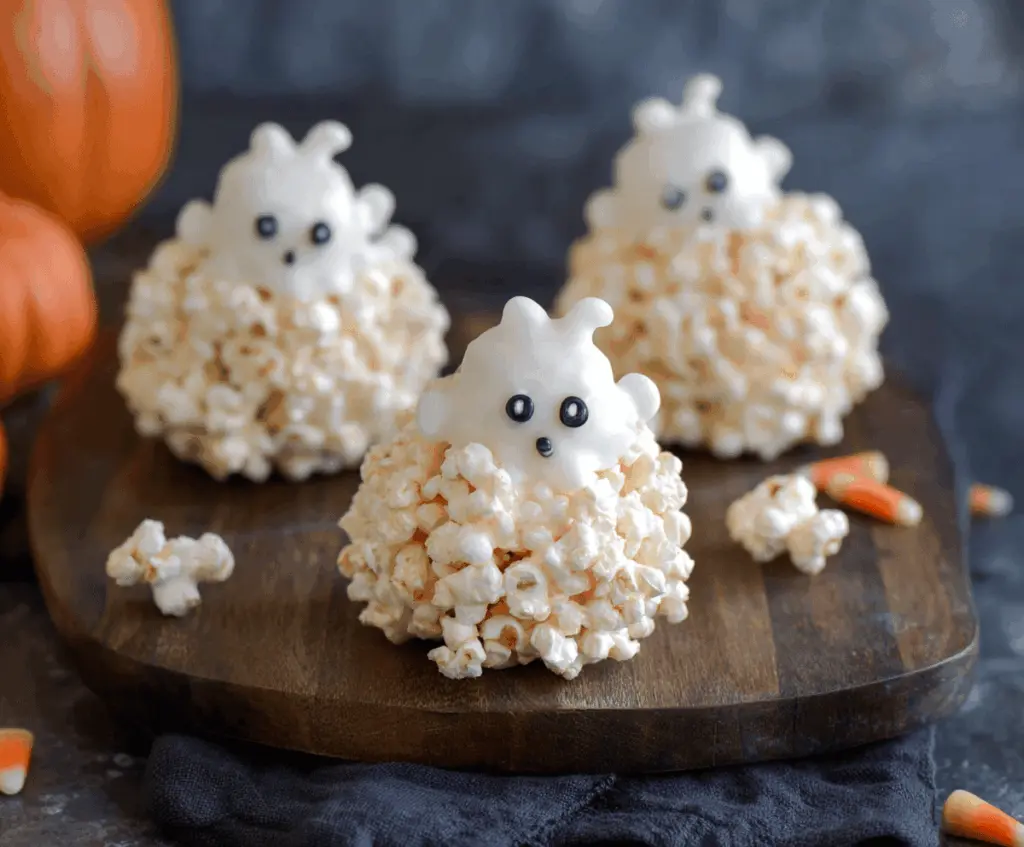 Spooky Ghost Popcorn Balls decorated with white icing and candy eyes for Halloween treat