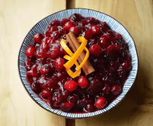 Vibrant orange and cranberry sauce with cinnamon, perfect for holiday meals.