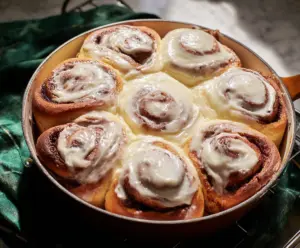 Delicious cinnamon rolls topped with creamy cream cheese frosting on a wooden table