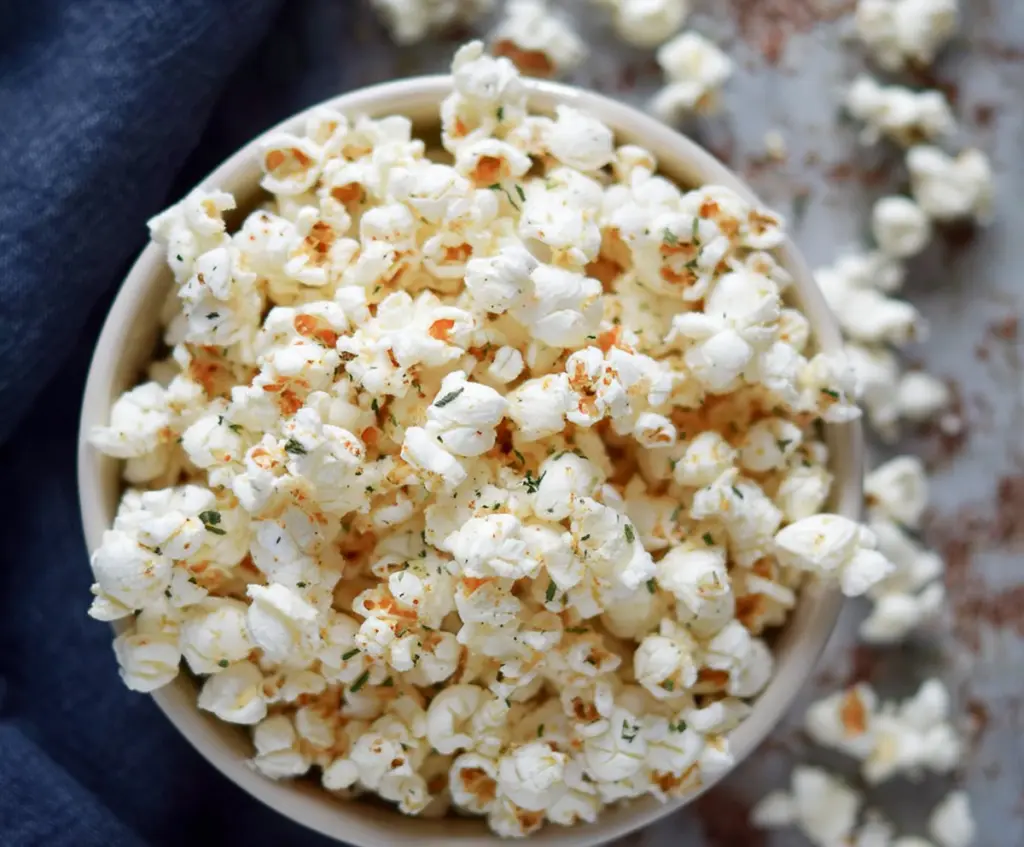 Golden Parmesan Truffle Popcorn garnished with fresh herbs in a bowl for a savory snack.