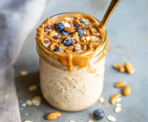 Creamy peanut butter overnight oats in a glass jar topped with fresh berries and chia seeds for a healthy breakfast