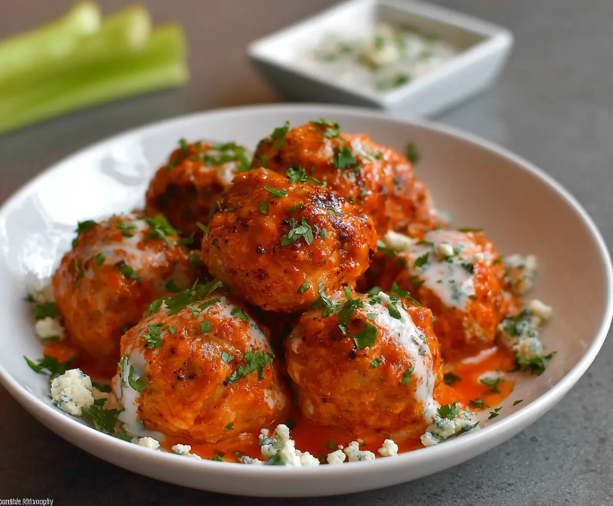 Delicious buffalo chicken meatballs served with a spicy buffalo sauce and fresh green herbs.