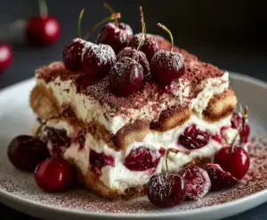 Delicious Cherry Amaretto Tiramisu dessert topped with fresh cherries and cocoa powder.
