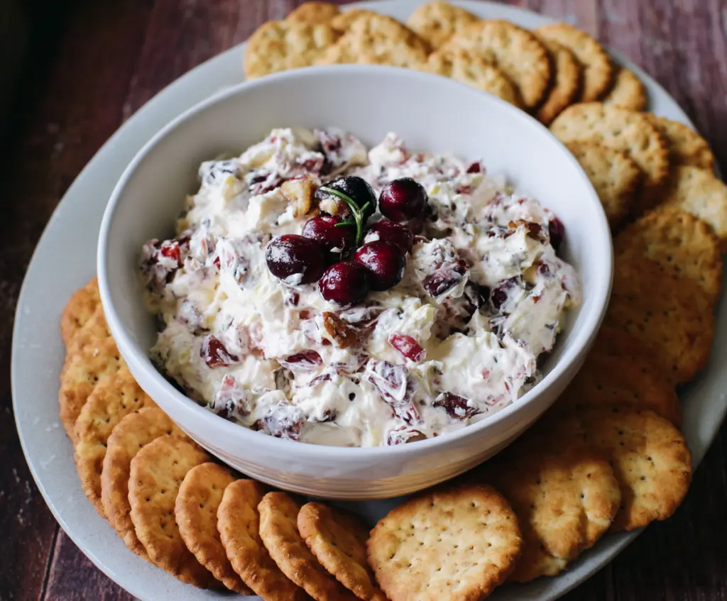Cream cheese dip with cranberries and walnuts ready for serving on a platter.