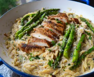 Delicious Parmesan orzo with tender chicken and fresh asparagus on a white plate.