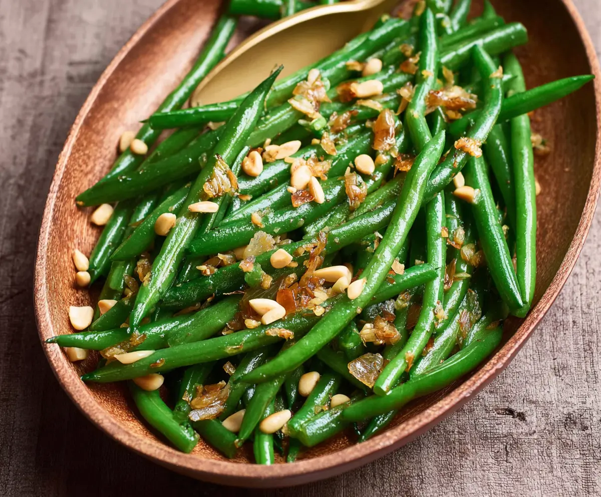 Delicious green beans garnished with roasted pine nuts, perfect for healthy side dishes.